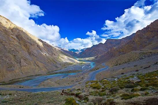 High mountain highway winding through rugged passes with glacial river running below in Ladakh August