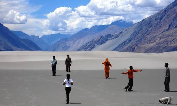 Travelers enjoying the Hunder sand dunes in Nubra Valley against mountain peaks in October
