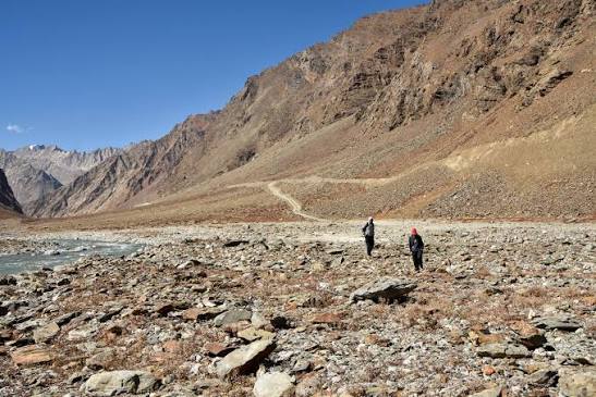 Explorers trekking near mountain pass road and glacial river in Ladakh in October
